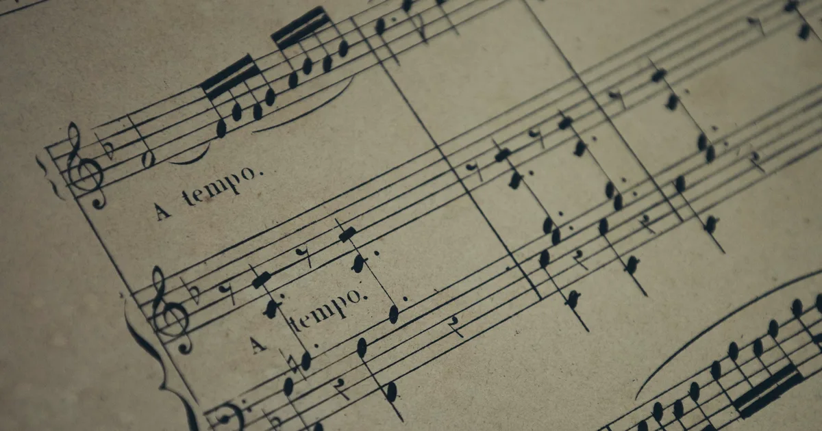 An upright piano in a quiet room with sheet music on the stand.