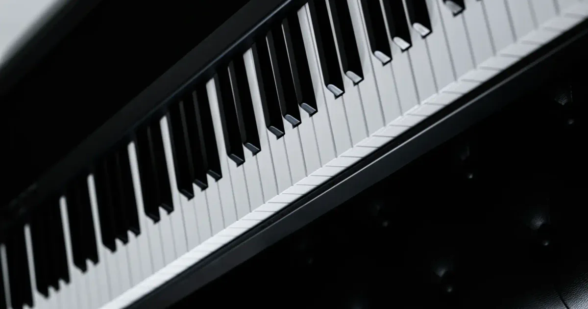 A close-up of the keys of a black grand piano, seen along the keyboard